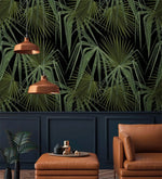 Green and black palm leaves wallpaper above navy wainscoting with twin copper pendants and tan leather chair