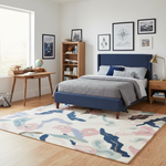 Modern bedroom with a blue bed, wooden desk, and colorful rug.