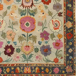 A vibrant hand-knotted area rug featuring an intricate floral pattern with colorful blooms in shades of pink, purple, and orange. The rug's border is adorned with complementary floral designs, adding elegance to any space.