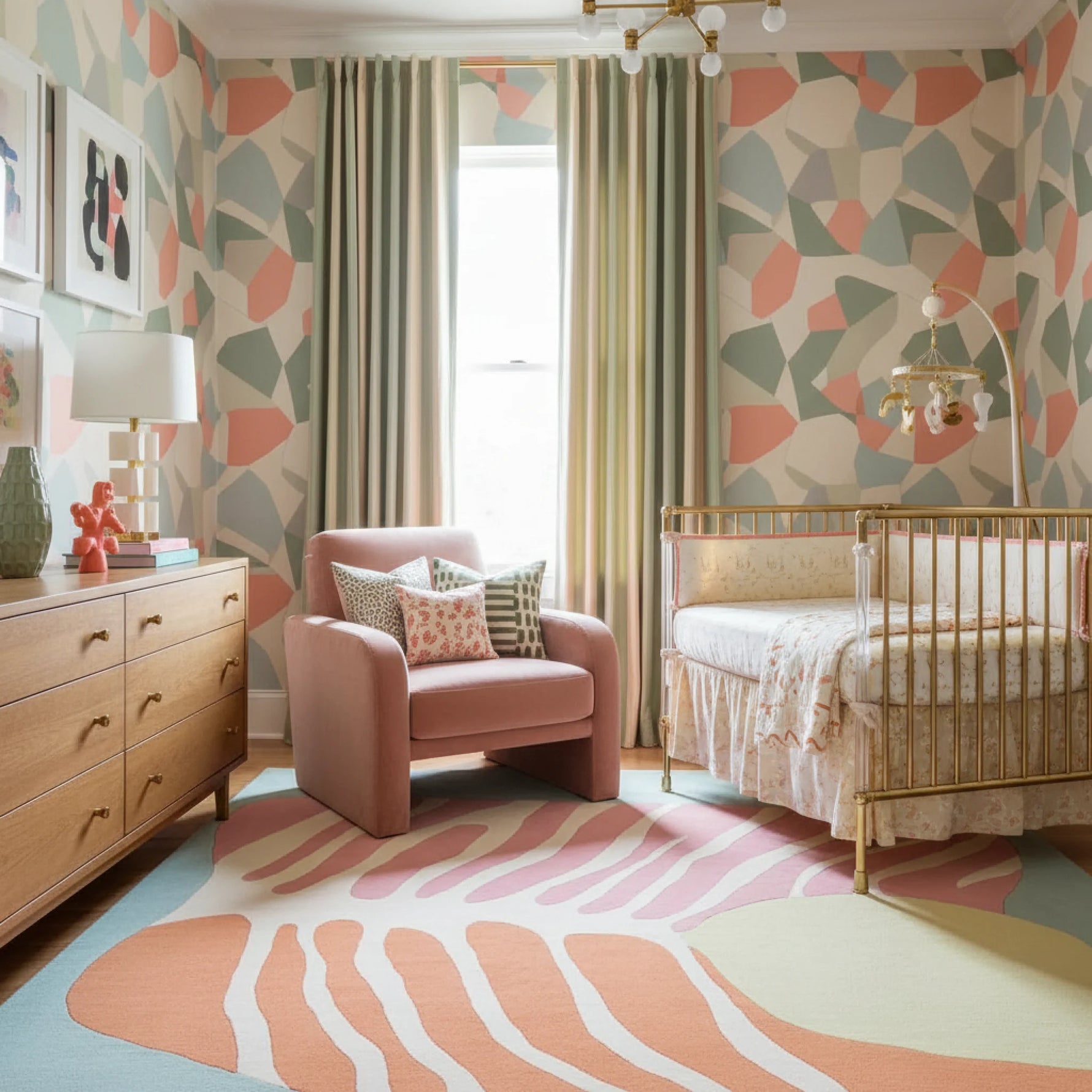 Children's room with geometric wallpaper, pink armchair, a contemporary wool rug, and crib.