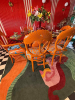 A vibrant, hand-tufted area rug with an abstract design featuring bold colors like orange, green, and pink. The rug adds a contemporary flair to the room, complementing the bright orange chairs and colorful decor. Perfect for adding a touch of style to a bedroom or office, this wool rug stands out as a statement piece.