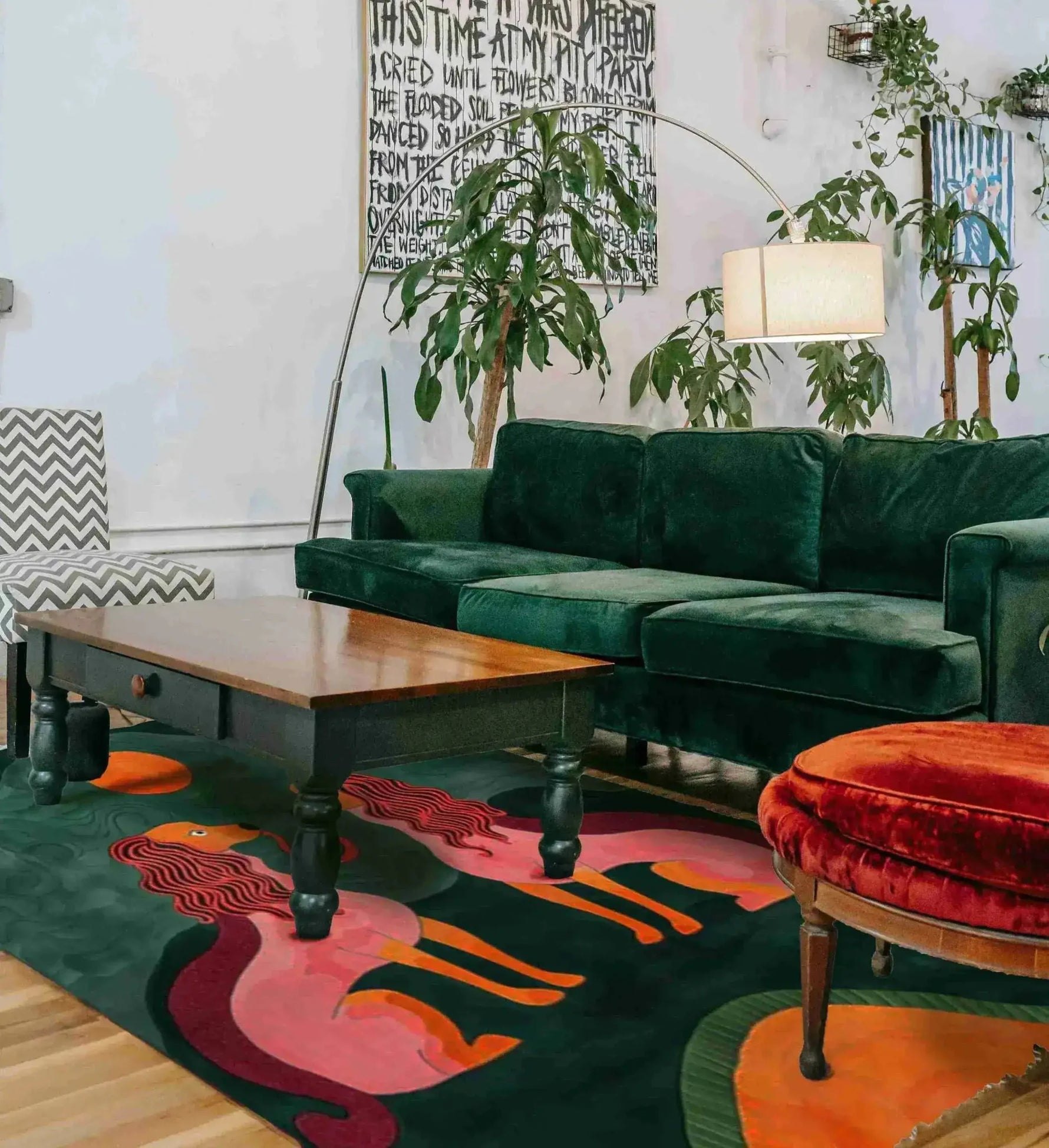 A stylish living room featuring a Duo Tails Hand Tufted Area Rug with a vibrant abstract design. The contemporary wool rug adds a pop of color under the wooden coffee table and velvet green sofa, perfect for a modern bedroom or office setting.