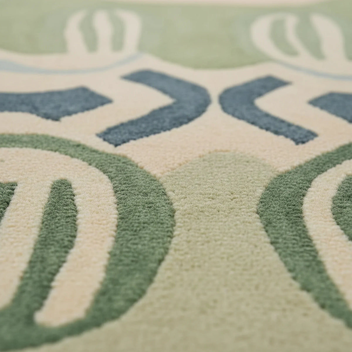 Close-up of a textured rug with circular patterns in green, blue, and beige.