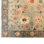 A beautifully detailed Elysian Bloom Knotted Wool Rug showcasing an intricate floral pattern with vibrant red, orange, and blue flowers on a soft gray background. The border features delicate floral motifs, enhancing the elegance of this area rug.