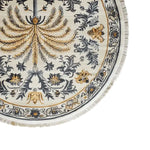 This elegant area rug showcases an intricate design with a central palm motif in golden hues, surrounded by detailed floral patterns in gray and gold on a light background. The round rug features a delicate fringe, adding a touch of sophistication to any room.