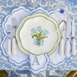 embroidered monogram placemat overhead view white scalloped blue border letter A napkin blue floral plate on blue tablecloth