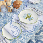 embroidered monogram placemat white scalloped blue border with A napkin monogram blue floral plate on blue botanical tablecloth