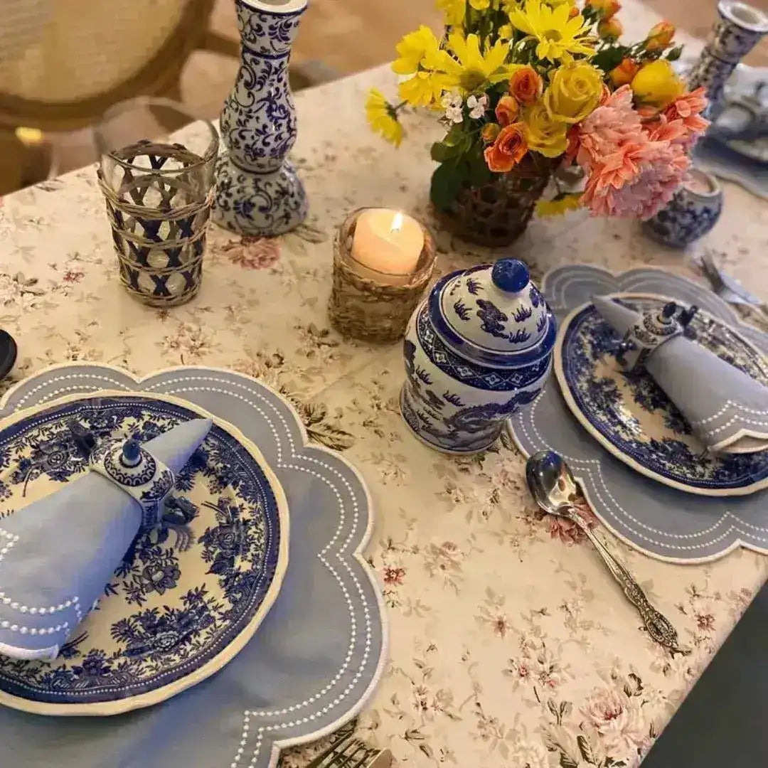 Embroidered Placemats with Beaded Detail table view — pale blue scalloped shape with bead-dot border, chinoiserie plates and candle