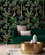 Emerald velvet sofa and gold drum table set against dark jungle foliage palm wallpaper