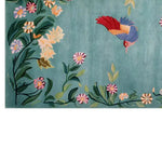 Vibrant area rug featuring a whimsical design with colorful flowers and a bird in flight against a soft blue background, showcasing intricate knotted wool craftsmanship.