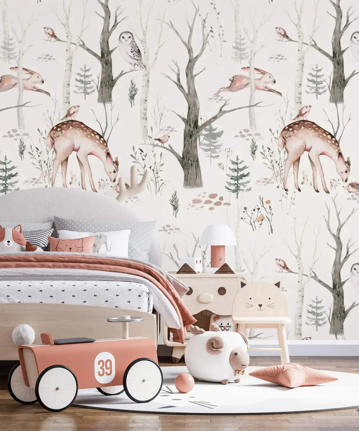 Enchanted Forest wallpaper with grazing deer and owls above a child's bed in peach bedding