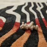 Close-up of a textured rug with black, white, and orange stripes.