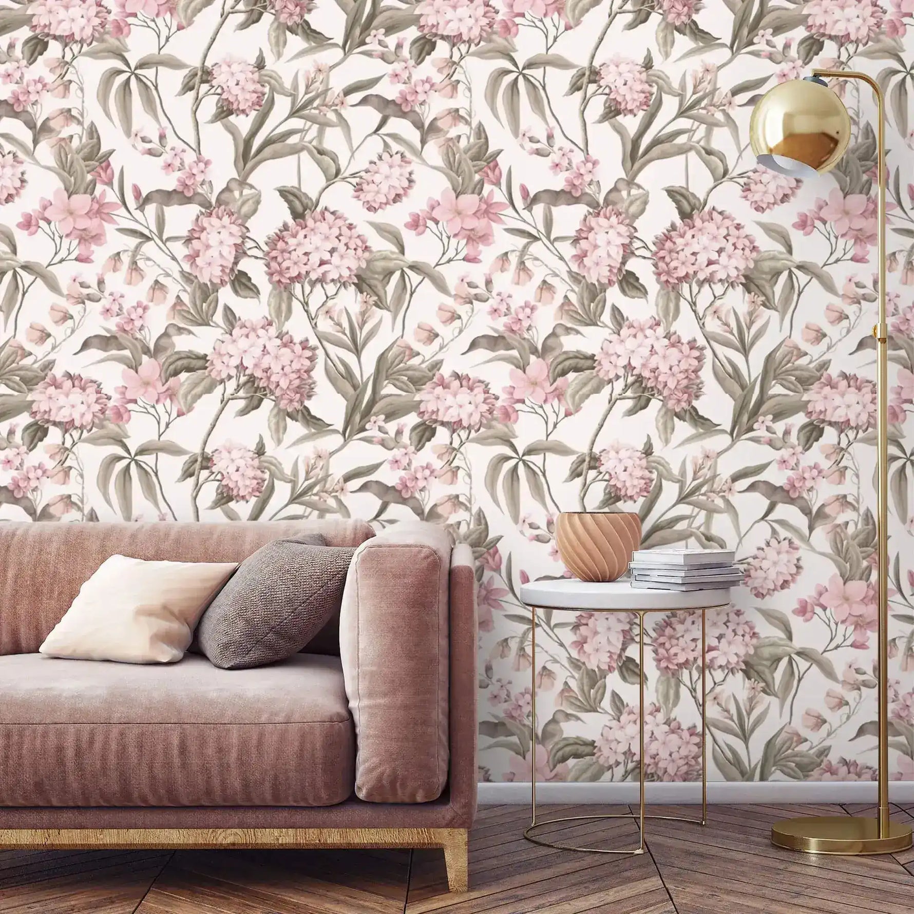 English Garden Wallpaper of pink blooms and sage leaves behind a blush velvet sofa, marble side table, and gold lamp.