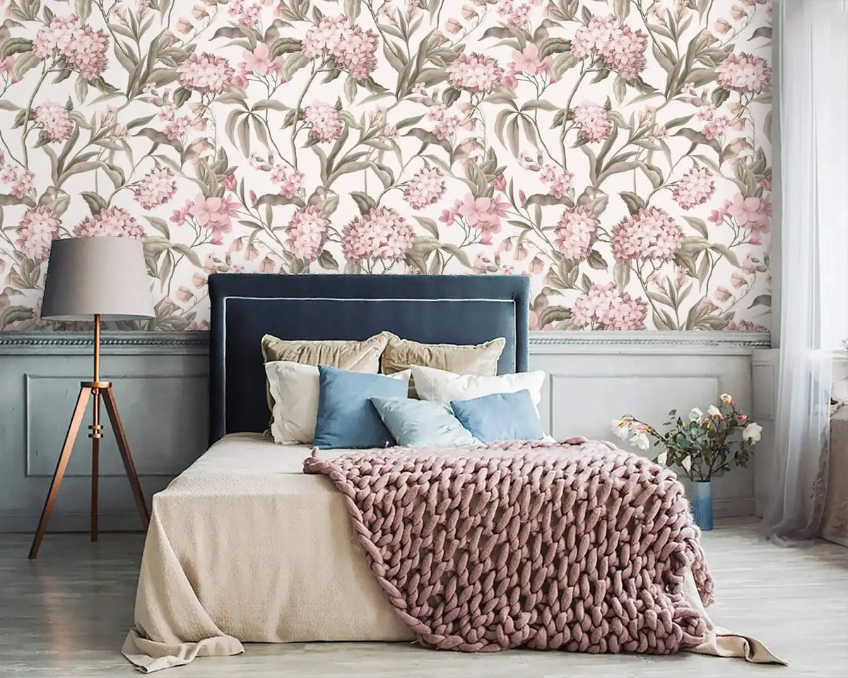 English Garden Wallpaper with large pink hydrangeas above a navy upholstered bed, pink knit throw, and tripod lamp.