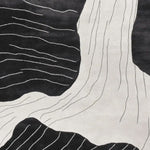 A contemporary area rug featuring an abstract black and white design resembling erosion stream veins. This hand-tufted wool rug is perfect for adding a modern touch to living room spaces. Ideal for those seeking stylish and unique living room area rugs.