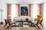 Modern living room with a white sofa, yellow chair, green rug, and abstract art on the wall.