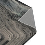 Corner detail of dark charcoal rug with swirling grey wave texture, folded corner reveals grey non-slip backing with zigzag stitching, Ethereal Archway Fluid Pathways Rug