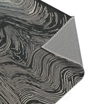 Close-up of folded corner on dark rug with cream-white flowing wave lines and grey canvas backing, Ethereal Archway Fluid Pathways Rug material detail
