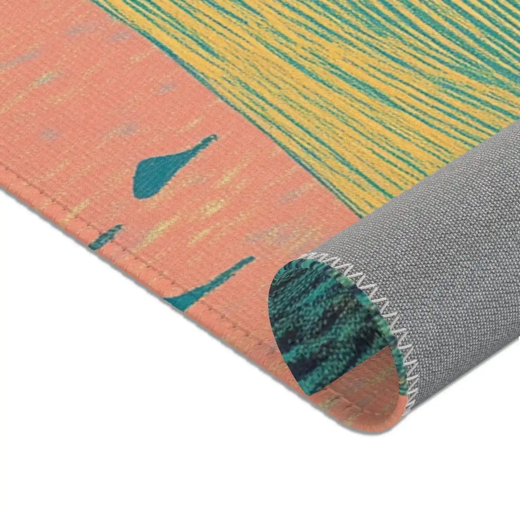 Corner roll of Ethereal Guardian Accent Rug showing peach border with teal bird silhouettes and gold striped field, gray backing with serged zigzag