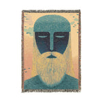 Woven fringed throw blanket with teal bearded guardian face, long golden beard, peach-blush sky and bird silhouettes, portrait