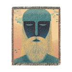 Square woven blanket with teal-headed mystical bearded figure, golden yellow beard on peach background, fringe trim