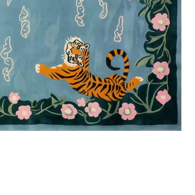 This vibrant area rug features a playful abstract tiger design on a serene blue background, bordered by lush green foliage and delicate pink flowers, capturing a unique blend of nature and artistry.