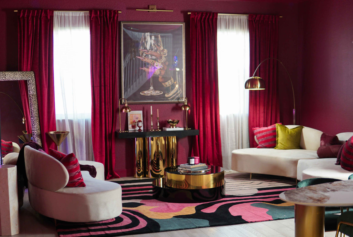 Abstract hand-tufted rug with swirling pink, black, teal, and gold shapes styled in a bold red living room