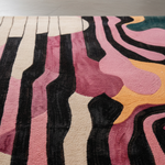 Close-up of a colorful abstract patterned rug with pink, black, and beige colors.
