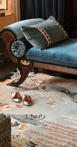 Blue velvet sofa with decorative pillows on a patterned vintage inspired  wool rug