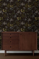 Fern blossoms monochrome wallpaper behind a dark walnut mid-century sideboard with round drawer pulls