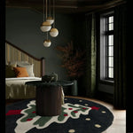 A cozy living room featuring a stylish round area rug with a festive evergreen design. The hand tufted wool rug is placed under a modern round table, complementing the elegant decor of the space. Ideal for an office or living room, this rug adds a touch of warmth and charm.