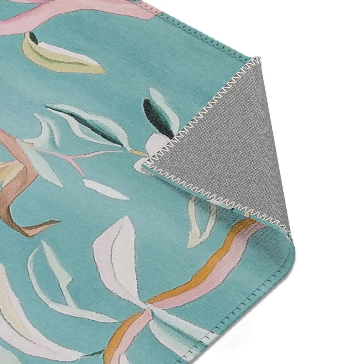 Corner of Floral Birds Accent Rug folded to reveal flat grey non-slip backing and stitched border on teal floral side