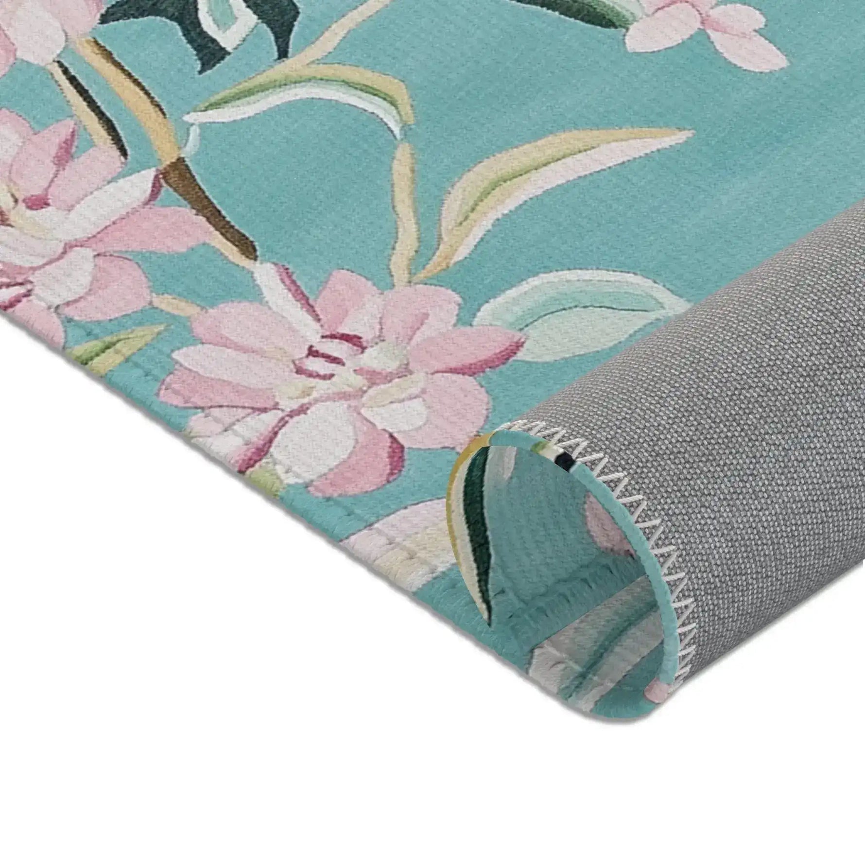 Bottom corner of teal Floral Birds Accent Rug showing pink blossoms and grey non-slip backing curled at corner