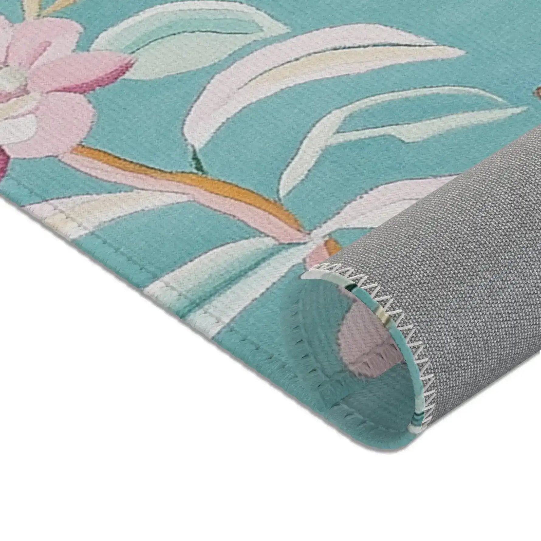Close-up corner of teal Floral Birds Accent Rug folded back showing grey non-slip backing and zigzag stitched border