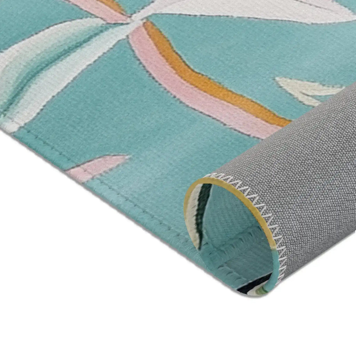 Close-up corner of teal Floral Birds Accent Rug with white leaf pattern, grey backing, and yellow zigzag stitched edge