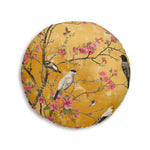 Round floor pillow with amber-gold background, multiple birds resting on blooming cherry branches, Floral Birds and Blossoms Floor Pillow close front