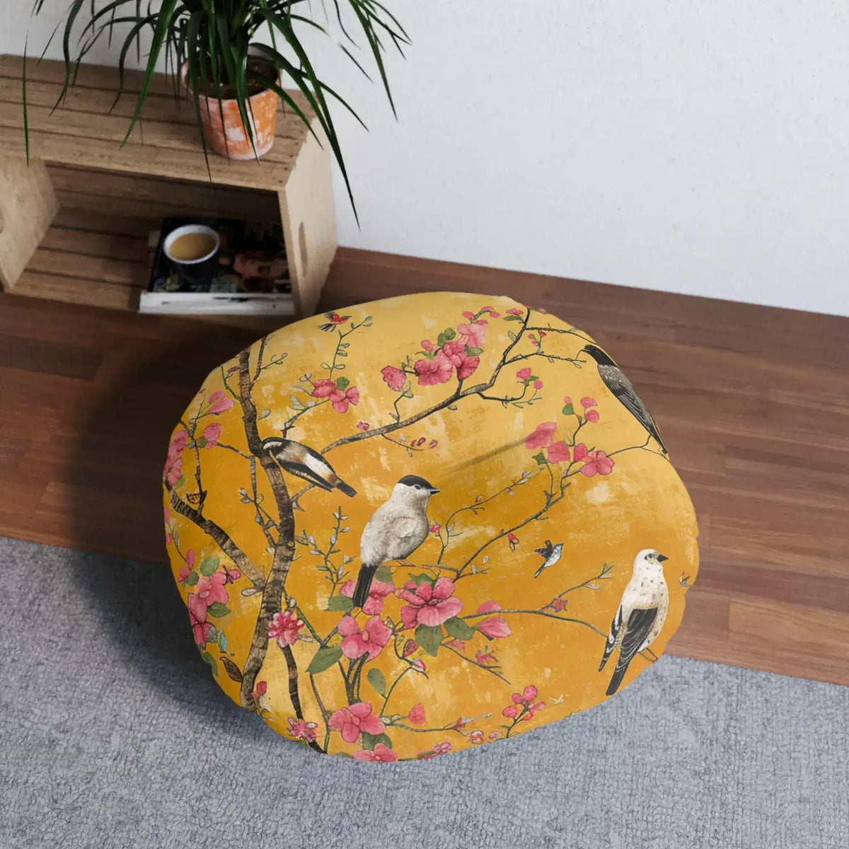 Round floor pillow on floor beside wooden shelf and palm plant, amber-gold floral birds print, Floral Birds and Blossoms Floor Pillow in-room lifestyle