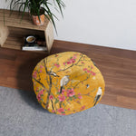 Single round floor pillow on hardwood floor near wooden shelf with plant, amber-gold birds-and-pink-blossoms print, Floral Birds and Blossoms Floor Pillow in room
