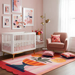 Nursery room with a white crib, colorful rug, and abstract art on the wall.