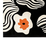 A stylish area rug showcasing a contemporary design with bold black and white wavy stripes and vibrant orange floral accents. This large wool rug is perfect for enhancing modern living room spaces with its unique and artistic pattern.