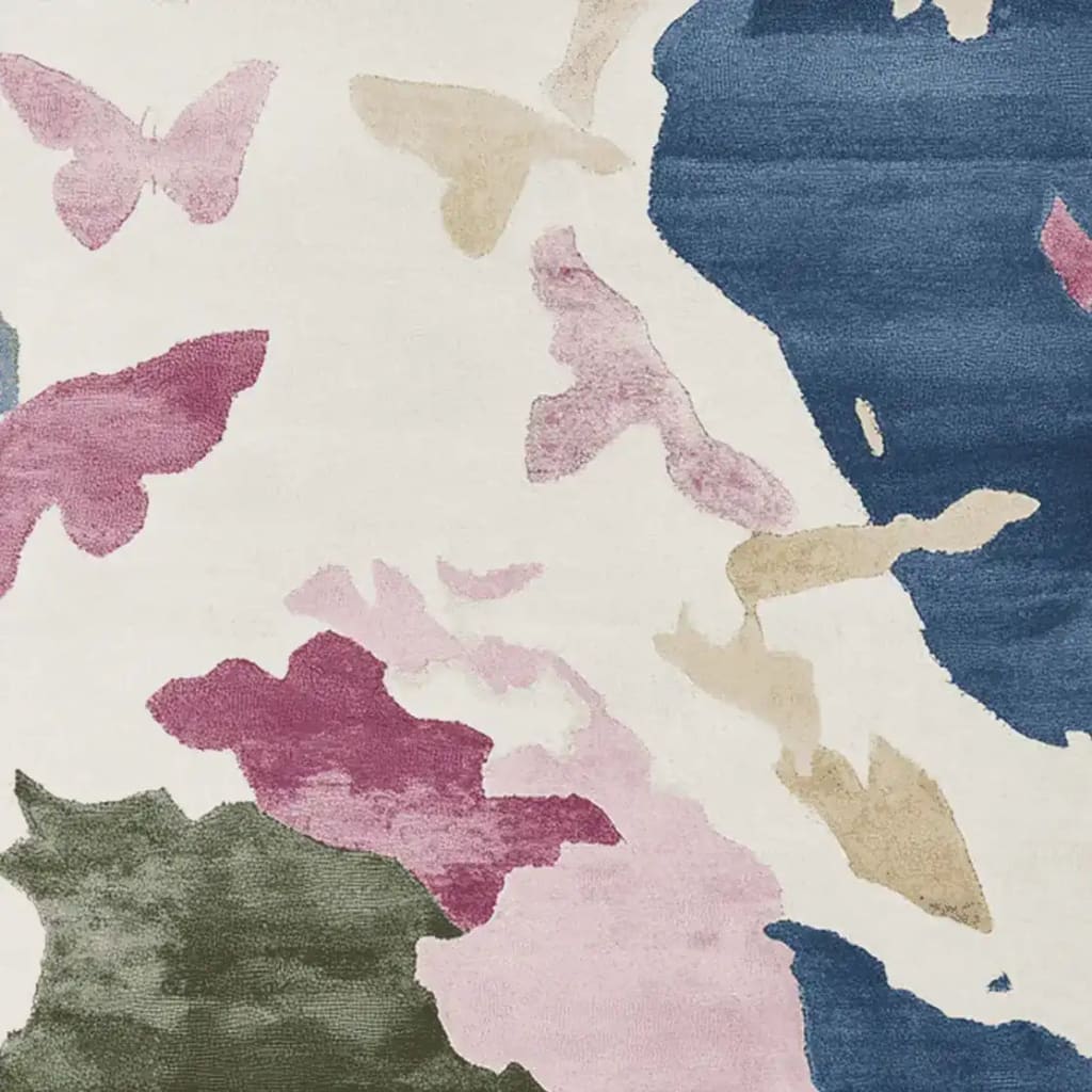 Close-up view of a Floral Drift Pattern Hand Tufted Rug, showcasing abstract butterfly motifs in shades of pink, green, and blue on a wool surface. This contemporary area rug is perfect for adding a touch of elegance to any living room.