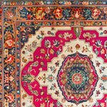 A vibrant Floral Fiesta Hand Knotted Area Rug showcasing intricate floral patterns with a rich color palette of pink, blue, and cream. This vintage square area rug, perfect for living or dining rooms, exudes elegance and is crafted from high-quality wool, reminiscent of classic Persian rugs.