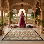 Woman in a traditional pink and gold outfit standing in an ornate room with a large patterned rug.