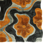 Top view of the Floral Groove Valley Hand Tufted Rug showcasing its vibrant abstract floral design. This contemporary area rug features bold orange and black swirls with intricate flower patterns, perfect for adding a touch of elegance to living room spaces. Made from high-quality wool, this living room area rug combines durability with artistic flair.