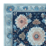 Close-up view of a Floral Mosaic Story Hand Tufted Rug, featuring intricate floral designs in soft blue and beige tones. This wool square area rug is perfect for adding elegance to living room spaces, offering a touch of sophistication and comfort.