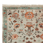 Close-up view of a Floral Scroll Harmony Hand Knotted Area Rug showcasing intricate floral designs in vibrant orange, teal, and beige tones. This 8x10 wool rug is perfect for adding an elegant touch to any living room.