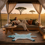 Woman sitting on a couch in a safari lodge and a deer rug, with a scenic view of the savannah.