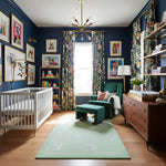 Nursery room with blue walls, rabbit rug, white crib, green armchair, and wooden dresser.