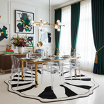 Modern dining room with a wooden table, an abstract round wool rug, clear chairs, and decorative elements.