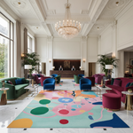 Luxurious hotel lobby with colorful rug, modern furniture, and chandelier.